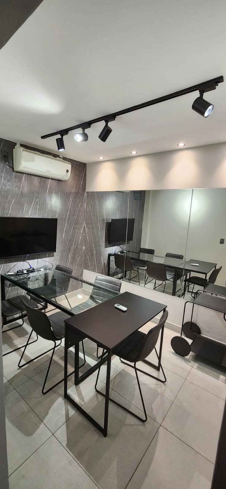 Sala Samambaia com parede de mármore escuro e mesa de vidro